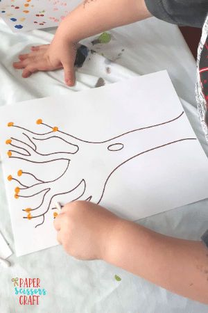 Child doing q-tip painting with a tree design.
