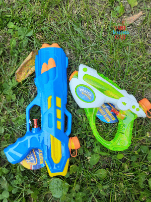 Two water guns laying in the grass.