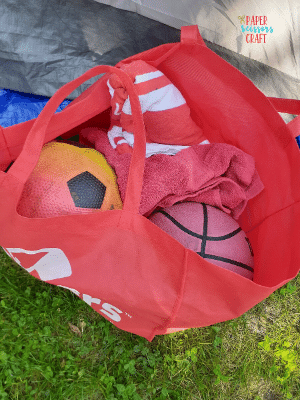 Red reusable bag with two balls and a towel.