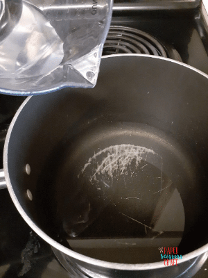 Pot on stove with water being poured into it.