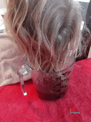 Girl dip dyeing her hair into Kool-Aid hair dye.