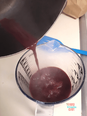 Hot purple liquid being poured into a glass measuring cup.