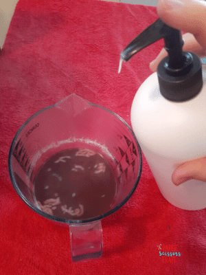 Conditioner bottle with pump being added to liquid Kool-Aid hair dye.