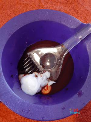 Hair dye brush in a Kool-Aid and conditioner hair dye mixture (before mixing).
