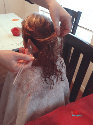 Applying Kool-Aid hair dye to girls hair using a dye brush.