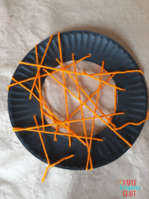 Paper plate spider web craft after being threaded.