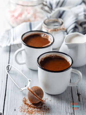 Two mugs of hot cocoa on a table.