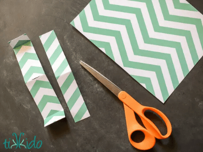 Green and white patterned paper partially cut into strips.