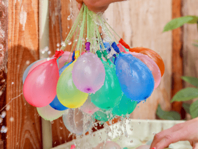 Bundle of water balloons filling up from a hose.