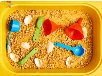 Container with plastic toys and edible sand (crushed cereal).