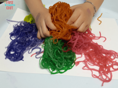 Child playing with noodles of various colors including orange, yellow, purple, green, and pink