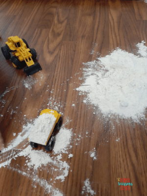 Yellow toddler construction trucks being played with in flour.