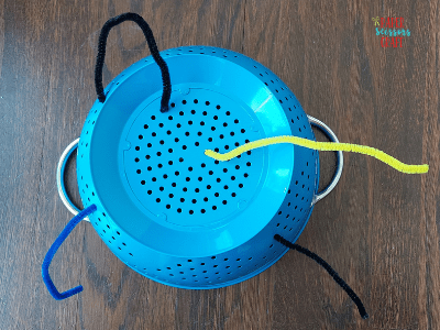 Kitchen strainer with pipe cleaners inserted in the bottom and sides.
