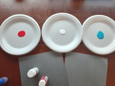 Red, white, and blue paint on three separate paper plates.