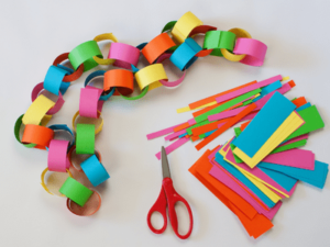 Construction paper and scissors with rings of colorful construction paper stringed together.