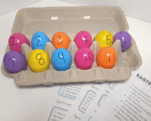 Plastic Easter eggs in an egg carton with numbers 1-11 written on them with black marker.