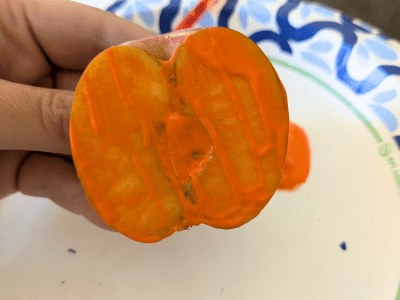 Apple cut in half and covered with orange paint to use for apple stamping.